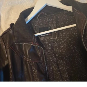 Mörkbrun skinnjacka från Fishbone XS - Snygg mörkbrun skinnjacka från Fishbone i storlek XS. Har några små skadade platser, kan skicka bild på det om du vill! Kan inte lägga den då man kan max ha 5 bilder. Skriv om du har frågor! (Btw lägger en samma annons som i min profil så flera kan upptäcka den:))