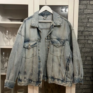 Oversized ljusblå jeansjacka - Säljer en oversized ljusblå jeansjacka med klassisk krage och knappar framtill. Jackan har två bröstfickor med lock och knapp, samt sidofickor. Perfekt för dig som gillar en chill och avslappnad stil.