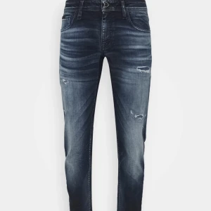 Mörkblåa jeans från Antony morato  - Snygga mörkblå jeans med slitningar och tvättade detaljer från Antony morato. Modellen har smal passform och klassisk femficksdesign. Jeansen har en modern slim fit siluett och är tillverkade i stretchig denim för extra komfort.