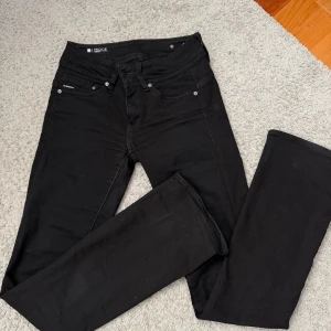 Svarta bootcut jeans G-Star RAW Midge - Svarta jeans från G-Star RAW, modell Midge Bootcut. Snygg passform med bootcut-ben. Jeansen har dubbla knappar bak i midjan. Använda fåtal gånger
