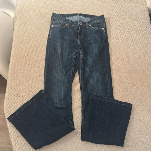 Mörkblå bootcut jeans - Snygga mörkblå jeans med klassisk bootcut passform. Jeansen har fem fickor, kontrastsömmar och stängs med dragkedja och knapp. Perfekta för dig som gillar en tidlös och avslappnad stil.