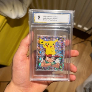 1999 Pokémon English Merlin Stickers Series 1 S2 Ash & Pikachu Holo - Samlarstickers från 1999 med Ash och Pikachu i holografiskt utförande. Perfekt för Pokémon-fans och samlare som vill ha något unikt och nostalgiskt i toppskick (Mint 9). En cool detalj till din samling! Kom med bud!!