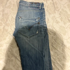 Dondup jeans - Snygga ljusblå jeans från Dondup med slitna detaljer och råa kanter vid benslut. Priset är fast och fraktar snabbt samma dag direkt, vill få sålda snabbt. Storlek 31. 