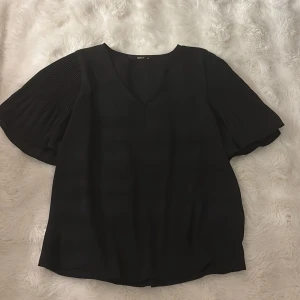 Svart blus med volang ärmar från ONLY - Säljer en svart blus från ONLY i storlek 34 passar även dig som bär storlek S/M. Blusen har v-ringad hals och korta, volang ärmar.  Materialet känns lätt och luftigt. Pris kan diskuteras💗