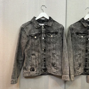 Grå jeansjacka med tvättad look - Snygg grå jeansjacka från Cubus med tvättad effekt och klassisk krage. Jackan har silverfärgade knappar framtill, två bröstfickor med lock och sidofickor. Långärmad modell med normal passform, perfekt för en chill streetstyle.