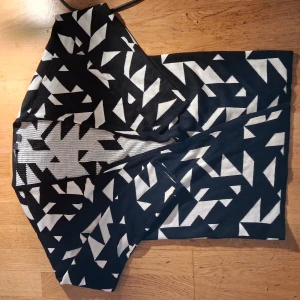 Svartvit mönstrad kofta Esmara - Snygg svartvit kofta från Esmara med grafiskt mönster i form av vita trianglar och former mot svart bakgrund. Koftan  är stickad och har en rak, kort modell som ger en cool och modern vibe. Perfekt för dig som gillar att sticka ut med mönster och kontraster.