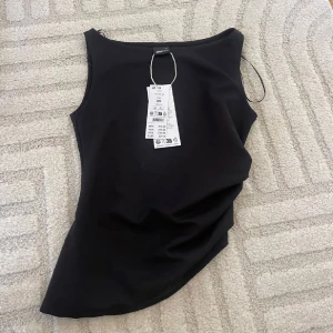 Svart ärmlös linnetopp från Zara - Snygg svart linnetopp från gina tricot i storlek XS. Toppen har en enkel och stilren design med rund hals och ärmlös passform. Perfekt att matcha med jeans eller kjol för en cool look. Materialet är mjukt och skönt mot huden.
