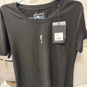 Svart t-shirt från RS Sports - Svart t-shirt från RS Sports med enkel design och liten vit logga på bröstet. Modellen är klassisk med rund hals och korta ärmar. Tillverkad i mjukt och lätt material som passar perfekt för träning eller chill dagar😊prislapp fortfarande kvar, oanvänd! 