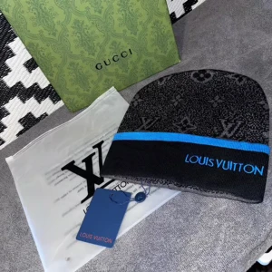 Svart mössa med blå kant - Svart och grå mössa från med diskret monogram och en blå rand längs kanten. Märkets logga är broderad i blått framtill. Snygg och trendig accessoar för dig som gillar lyxiga detaljer.