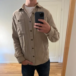 Overshirt med knappar - Dobber - Säljer denna sjukt snygga Overshirten från Dobber⭐️ Färgen är beige och storleken är L✅ Overshirten har inga defekter och skicket är utomordentligt🙌🤝 Sjukt najs passform och passar perfekt till hösten🍁🙌 Tveka inte på att höra av er dig vid minsta fråga eller fundering😊