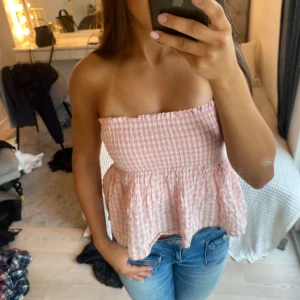 Rosa och vit rutig volangkjol - Supersöt kort kjol i rosa och vitt med rutigt mönster och volanger. Jag har vilt ner kanten på kjolen på de första bilderna så den blir lågmidjad. Köpte den på Kappahl barn för tre år sedan men den kommer inte till användning så därför säljer jag den. Storleken passar från XS-M   