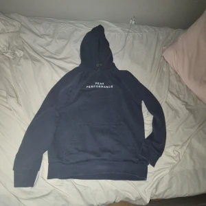 Mörkblå hoodie från Peak Performance storlek m - Säljer en mörkblå hoodie från Peak använd ett par gånger Performance med vit logga på bröstet. Klassisk modell med huva, känguruficka och ribbade muddar. Perfekt för chill dagar eller när du vill ha en enkel och snygg look.