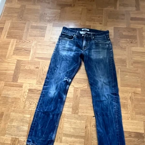 Blå jeans från Quiksilver, regular fit - Säljer ett par blå jeans från Quiksilver i regular fit. Klassisk femficksmodell med slitna detaljer och kontrastsömmar. Jeansen har rak passform och är tillverkade i robust denim. Perfekt för dig som gillar en avslappnad och tidlös stil.