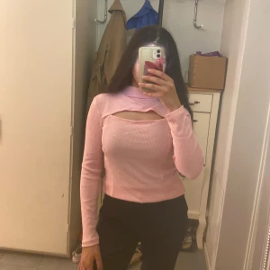 Rosa ribbad långärmad polotopp - Trendig ljusrosa ribbad polotopp med lång ärm och unik cut-out detalj över bröstet. Den är i storlek S. Hör av er ifall ni har några frågo🩷🩷