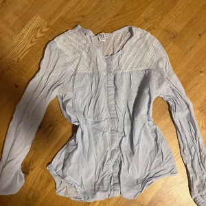 Ljusblå blus från Saint Tropez XS - Supersöt ljusblå blus från Saint Tropez i tunn bomull. Har broderade detaljer upptill, knappar framtill och lång ärm. Perfekt för dig som gillar romantisk och feminin stil. Sitter snyggt med lätt figursydd passform.