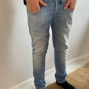Ljusblå skinny jeans från Dondup - Säljer ett par ljusblå slim jeans från Dondup, modell George. Jeansen har klassisk femficksdesign, knappgylf och snygg tvättad look. Tillverkade i mjuk bomullsdenim med en smal passform som sitter tajt hela vägen ner. W29 längd 90cm