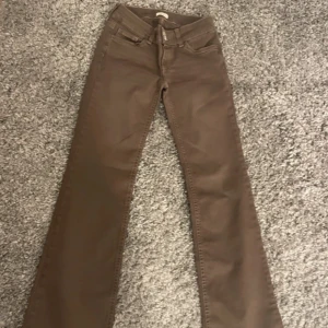 Bruna bootcut byxor från Nelly - Snygga bruna byxor från Nelly med bootcut-modell och klassiska fickor bak med dekorativa sömmar. Byxorna har två knappar i midjan och är tillverkade i ett mjukt bomullsmaterial. Aldrig använda ❤️
