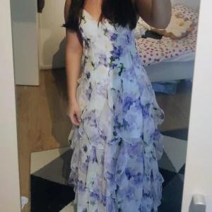 Lång blommig volangklänning - Säljer min otroligt fina klänning, då jag måste få lite mer plats i garderoben. Den är bra längd för mig som är 165 cm. Hör av dig vid funderingar 🥰💗