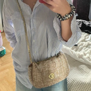 Väska zara - En söt liten väska från zara i tygmaterial med guldkedja o gulddetaljer! Köpt för några årsedan. Fortfarande fint skick kan vara lite färgslitningar på kedjan o knappen som man stänger väskan med!