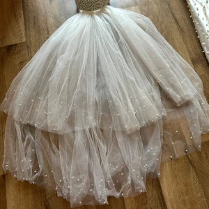 Vit långklänning med pärlor - “Brudklänning med accessoarer: brudbukett, väska och två underkjolar.