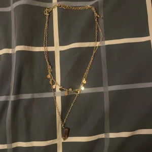Guldigt lager-på-lager halsband - Snyggt halsband i guldton med dubbla kedjor. Ena kedjan har små runda hängen och den andra har ett mörkt, rektangulärt hänge. Perfekt för att ge outfiten lite extra edge och trendig känsla.