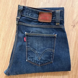 Levi's 506 Standard jeans blå - Klassiska Levi's 506 Standard jeans i mörkblå denim med raka ben och normal passform. Snygga kontrastsömmar, femficksmodell och ikonisk röd Levi's-tag på bakfickan. Perfekta för dig som gillar en tidlös och avslappnad look.