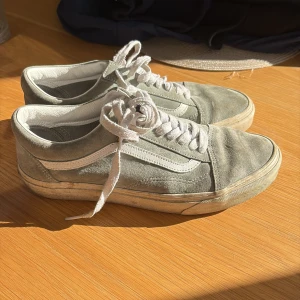 Gråa Vans Old Skool sneakers mocka - Säljer ett par Vans Old Skool sneakers i ljusgrå mocka med vita detaljer och klassisk sidorand. Skorna har vit platt sula, rund tå och vita snören. Insidan är fodrad i vitt och de är vattenavvisande enligt etiketten. Perfekta för en avslappnad streetstil.