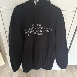 Svart hoodie Ant Wan Tele2 Arena - Svart hoodie från Ant Wan med vit text och coolt färgglatt tryck på ryggen från Tele2 Arena-konserten i Stockholm. Tröjan har huva, känguruficka och långa ärmar. Perfekt för dig som vill sticka ut med en unik konsertmerch!