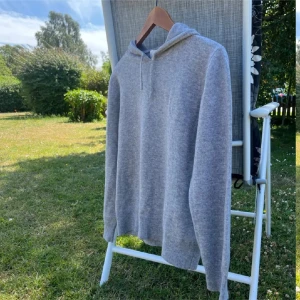 Grå kashmirhoodie från Sayless - Mysig grå hoodie från Sayless i mjuk kashmir. Tröjan har huva med snörning, långa ärmar och ribbade muddar. Perfekt för dig som gillar en enkel och stilren look med extra lyxig känsla.