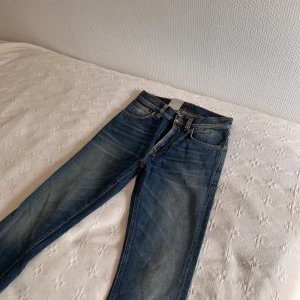Nudie Jeans Fearless Freddie W26 L32 - Säljer ett par blå Nudie Jeans Fearless Freddie med klassisk orange söm på bakfickorna. Jeansen har rak passform, normal midja och är tillverkade i bomull. Sjukt bra wash på dom. 