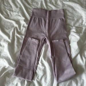 Ribbade lila leggings från H&M Sport - Säljer ett par ribbade leggings i ljuslila från H&M Sport. De har hög midja och är tillverkade i ett stretchigt material som passar perfekt för träning. Supersnygga och bekväma med en tight passform. Använda 3-4 gånger, i fint skick. Säljer eftersom dom är för små för mig.