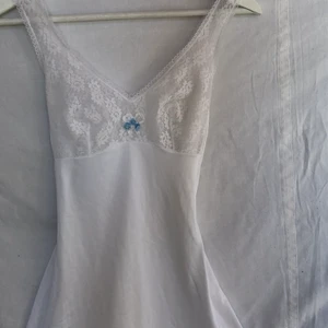 Nattlinne  - Unikt fint vitt nattlinne med broderad rosett mellan brösten. Bystdelen är genomskinlig och på sista bilden ser man den med en vit bh under. Gott second hand skick. Köpare står för frakten. 