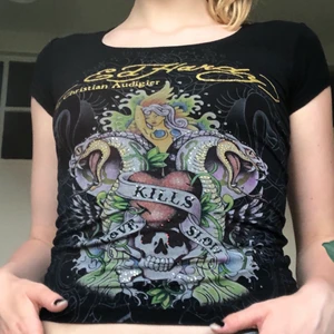 Ed Hardy T-shirt  - Skitsnygg Ed Hardy topp/T-shirt. Den är i dom modell så den sitter lite tajtare. Några stenar har åkt av men utöver det är är den i toppskikt 