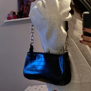 Skinnväska med kedjor - En jättefin skinnväska med kedjor som är i bra tillstånd. Väskan har en ”skada” på ena sidan därav säljs väskan billigt. Skadan syns dock inte om man väljer att ha väskan på andra sidan.