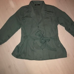 Grön blus - Grön blus från ginatricot, storlek 36. Band i midjan som kan knytas båda bak och fram. Sparsamt använd.