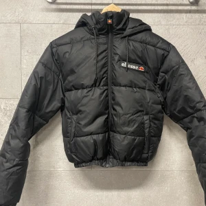 Ellesse kort pufferjacka - Säljer denna jackan då den inte kommer till användning. Köptes för runt 1000-lappen och endast använd en gång, snygg och bekväm. OBS kort modell ! Passar mig som har strl 36