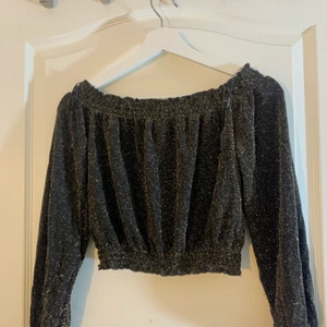 Croppad, glittrig off-shoulder topp  - Säljer denna topp då jag inte använder den. Sitter super fint på mig som är 178 cm lång, men den funkar om man är kortare. Glittret är åt det guldiga hållet. Skriv för bilder/ bilder med plagget på. Köpare står för frakt och pris kan diskuteras vid snabb affär❣️