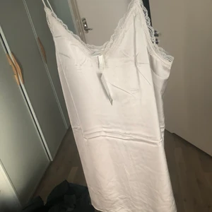 Klänning i satin - Helt ny och oanvänd klänning i satin med spetsdetalj. Storlek L. 