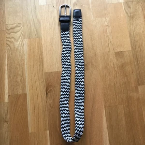 Svart-vitt belte - Ett svart-vitt belte som är ca. 100 cm lång och 3 cm bred. Den består av små rep som är ihop flätna. Det finns inga hål, den passar liksom till alla storlekar. 