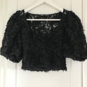 Topp med blommor  - En jättesöt svart croptop som har små svarta blommor  på sig🌸🖤 sitter tight på kroppen och har puffärmar