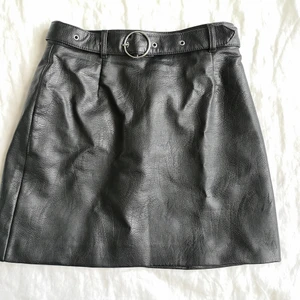 Kjol i fejkläder med bälte - Stl. 36, jättefint skick. Använt fåtal gånger. Ingår bälte. Pris går att diskutera. 