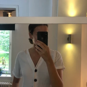 Vit topp med knappar - En fin och trendig topp med knappr från Lindex. Endast använd ett fåtal gånger och är i storlek XS men passar även XS. 50kr eller högst bud!