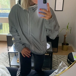 Reflexjacka outdoor - Outdoorjacka i reflextyg från Clique. Luva och två fickor med dragkedja. Perfekt för sena kvällspromenader. Herrmodell i storlek L.