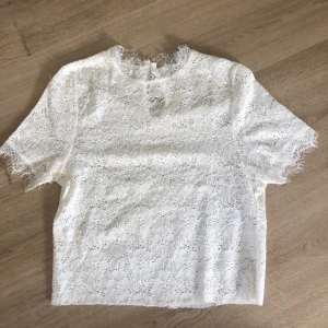 Spetstopp - Säljer nu denna spetstoppen i färgen vit, den sitter väldigt fint, jag har klippt den kortare vid magen så den är nu en topp istället för en t-shirt. Väldigt bra skick, den har knäppe i nacken. Frakt tillkommer🙂