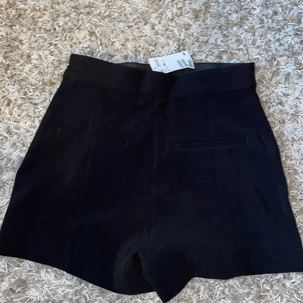 Oanvända svarta shorts med gulddetaljer från H&M, lappen kvar. . Shorts.