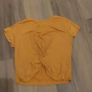 Gul tshirt med knyt detalj - Helt oanvänd gul T-shirt/topp med knyt detalj framtill, prislappen kvar 
