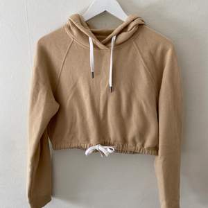Snygg och mjuk croppad hoodie i en fin beige färg. Den är använd fåtal gånger. Skön att ha både när det är svalt och varmt då den inte är så tjock. Från Hollisteg. Säljer på grund av inte min stil längre så används inte. 