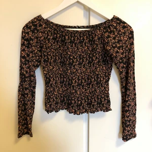 Shirrad blommig topp - Långärmad i otroligt mjukt tyg. Torson är av shirrat (rynkat/stretchigt) tyg. Sk. ”lettuce hem” i nedre kanten. Kan bäras som off shoulder, men även som vanligt. Från Gina Tricot i storlek M, passar även S. Knappt använd. •Samfraktar gärna•