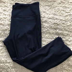 Träningsbyxor i storlek M - Trekvartslånga träningstights i mörkblå färg, storlek M. Använda vid 2 tillfällen. Detaljen är placerad vid benslutet på vardera sida. 