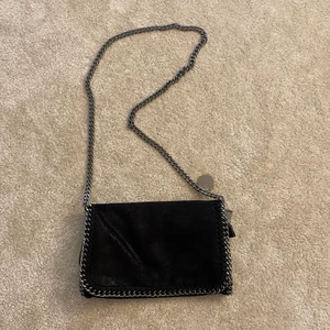 Stella McCartney liknande väska - Säljer en super fin Stella McCartney liknande väska i svart skimrig färg💞💞 Det får även att sjustera kjedjebandet som jag gillar! Som ny på utsidan men lite fläckar inuti, tycker inte dom förstör väskan på något sätt❤️ 